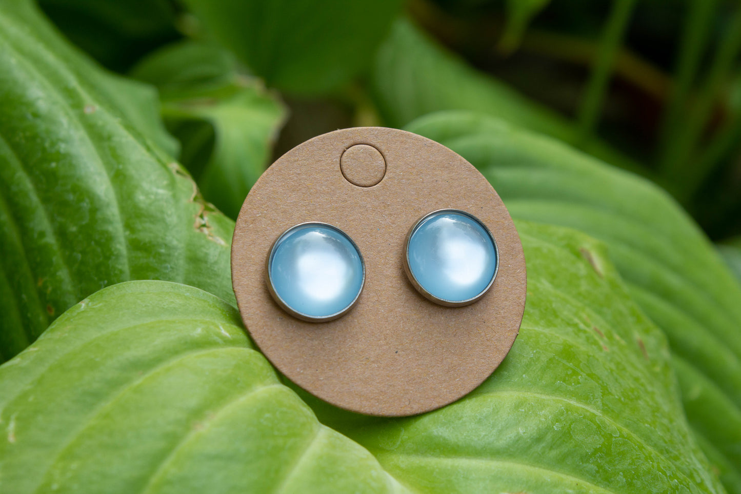 Világos kék színű cabochon fülbevaló, választható arany színű, rosegold színű, vagy ezüst színű alapban. 12 mm-es átmérőjű, nikkelmentes, így nem bántja az arra érzékeyenk fülét.