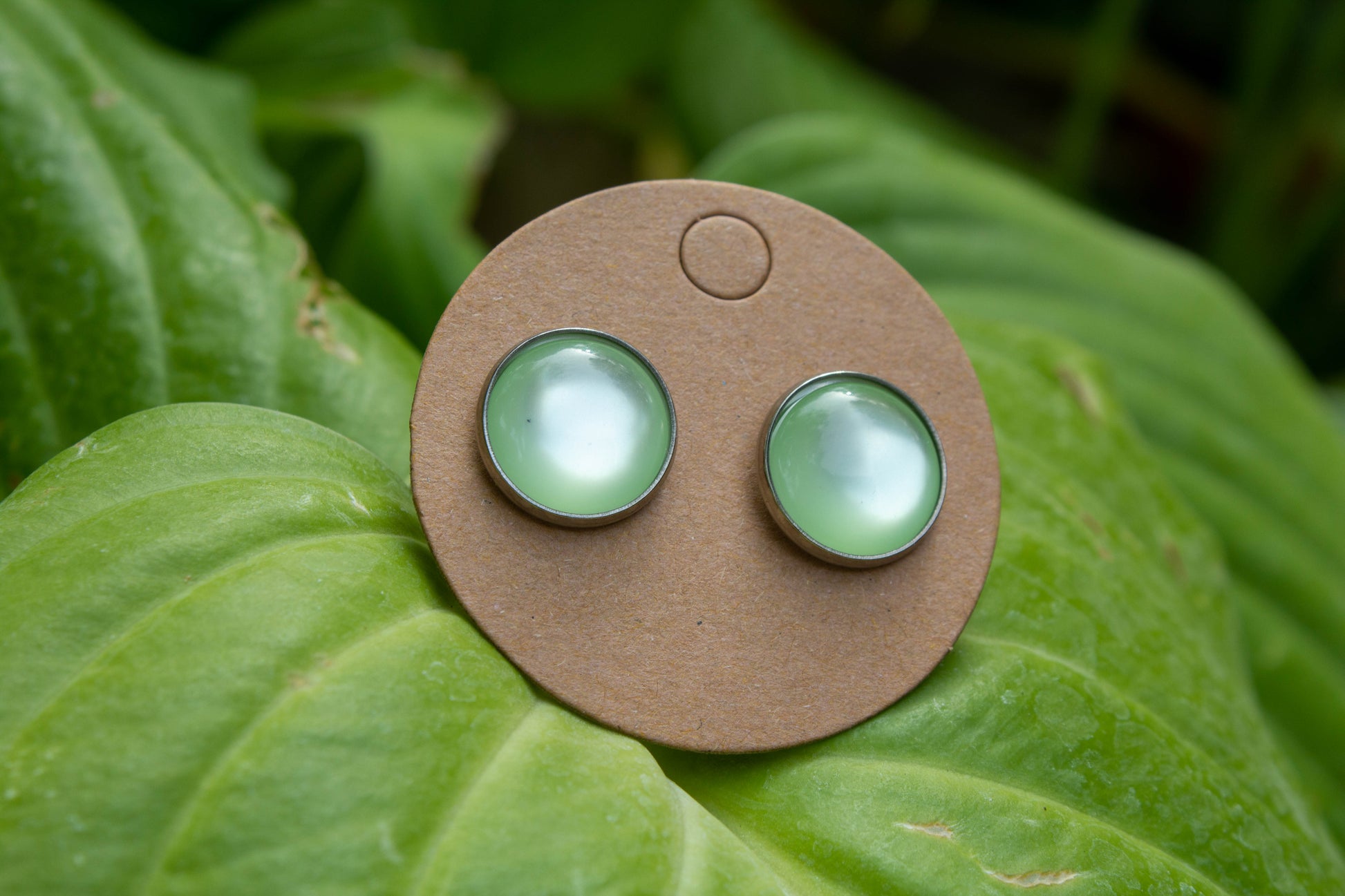 Világos zöld színű cabochon fülbevaló, választható arany színű, rosegold színű, vagy ezüst színű alapban. 12 mm-es átmérőjű, nikkelmentes, így nem bántja az arra érzékeyenk fülét.