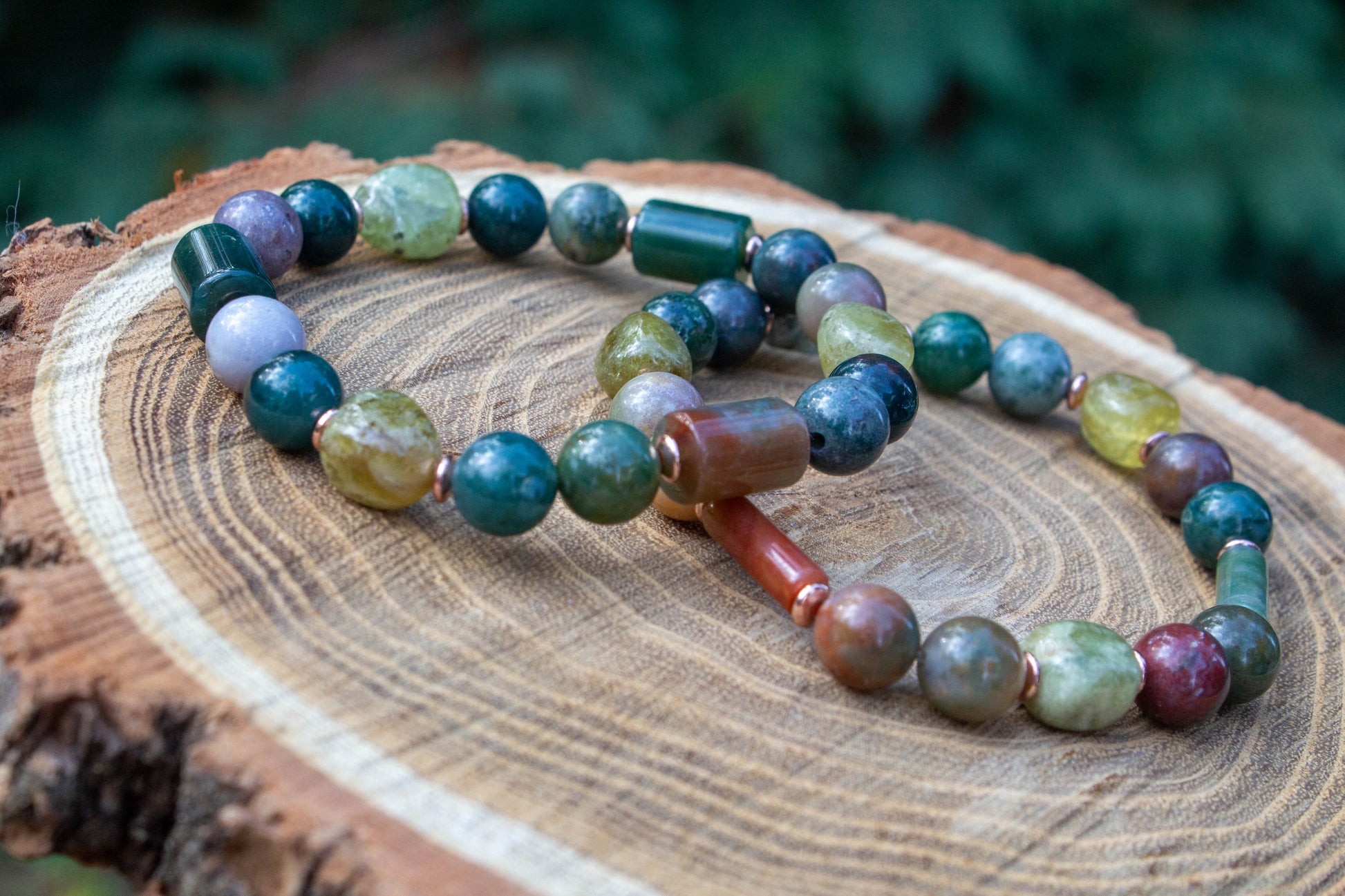 egyedi női karkötő indiai achát és gránát grossulat ásványokkal, indiai achát hasábbal, valamint rosegold hematatit köztessel, természtes fa háttérrel