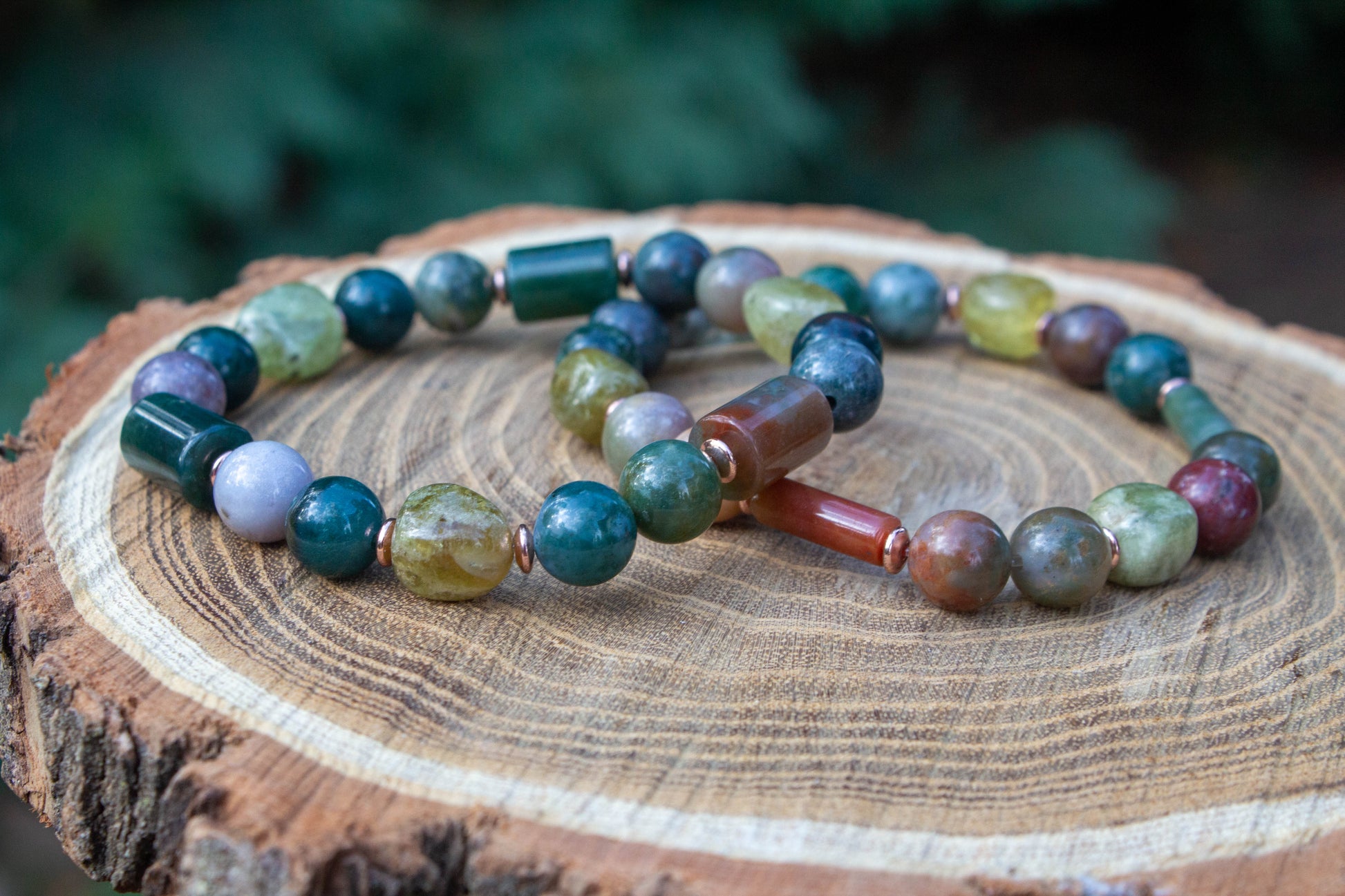 egyedi női karkötő indiai achát és gránát grossulat ásványokkal, indiai achát hasábbal, valamint rosegold hematatit köztessel, természtes fa háttérrel