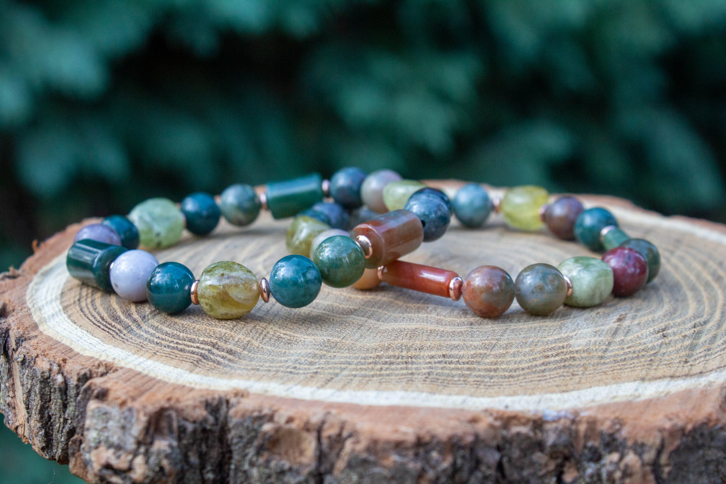 egyedi női karkötő indiai achát és gránát grossulat ásványokkal, indiai achát hasábbal, valamint rosegold hematatit köztessel, természtes fa háttérrel