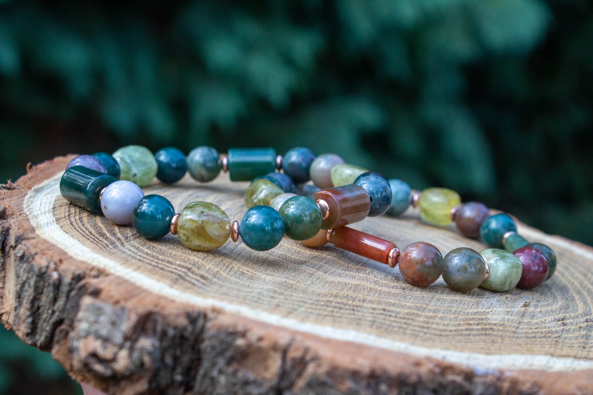 egyedi női karkötő indiai achát és gránát grossulat ásványokkal, indiai achát hasábbal, valamint rosegold hematatit köztessel, természtes fa háttérrel
