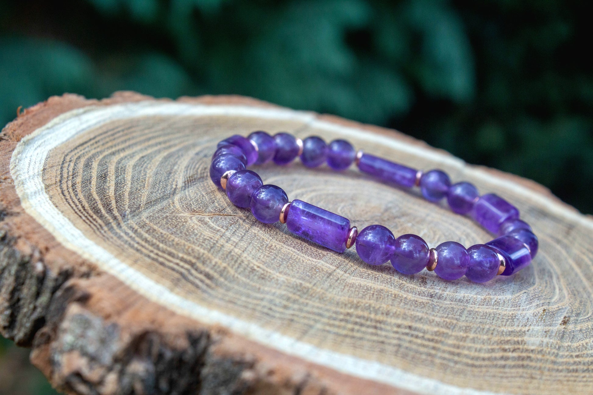 kézzel készült ametiszt karkötő ametiszt gyöngy és hasábok felhasználásával, rosegold hematit korongokkal, fa felületen fotózva, a Lila Harmónia kollekcióbóll