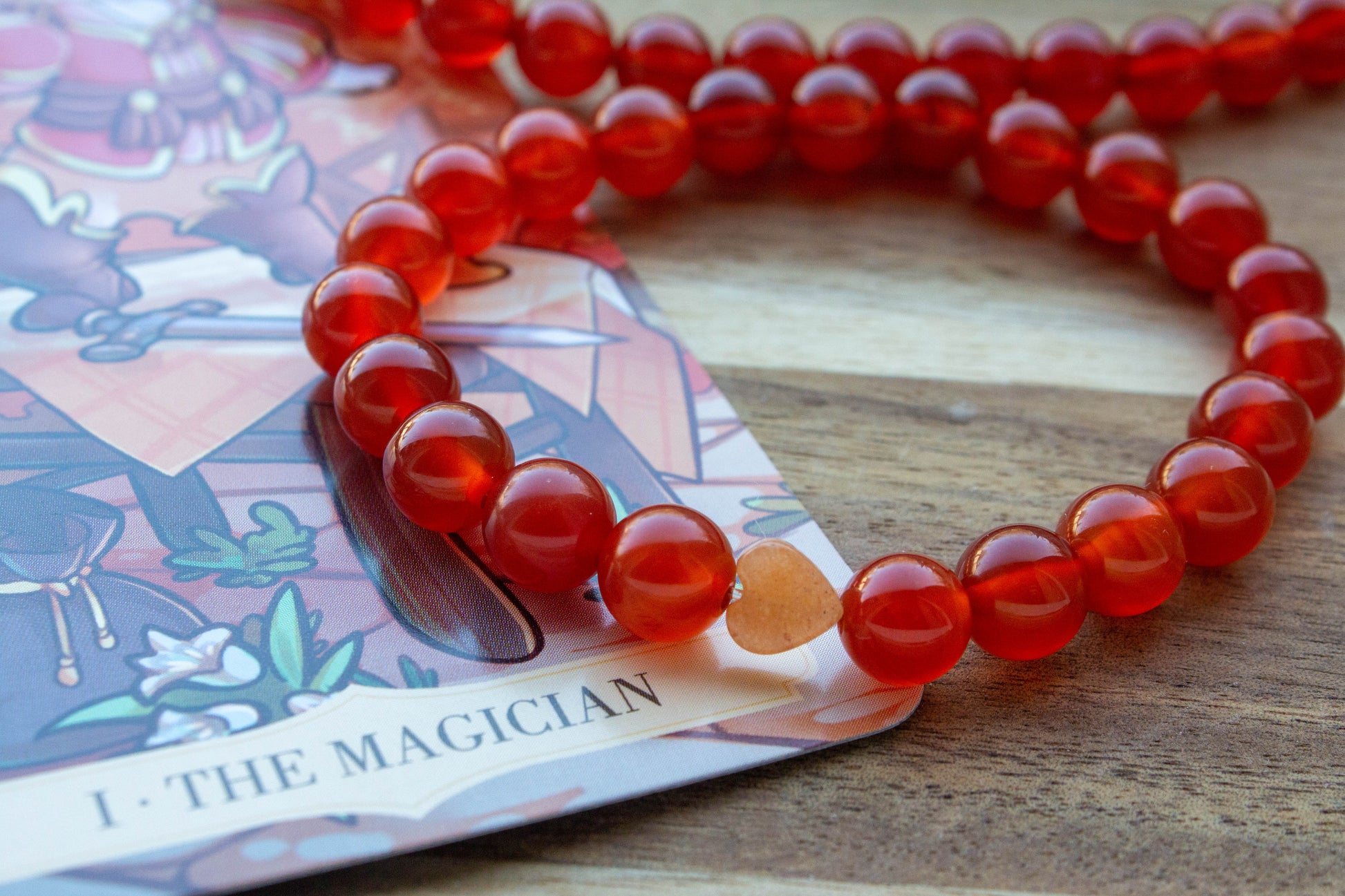 karneol ásványkarkötő, teremtő tűz energiával, spirituális ékszer, a háttérben mágus tarot kártyával