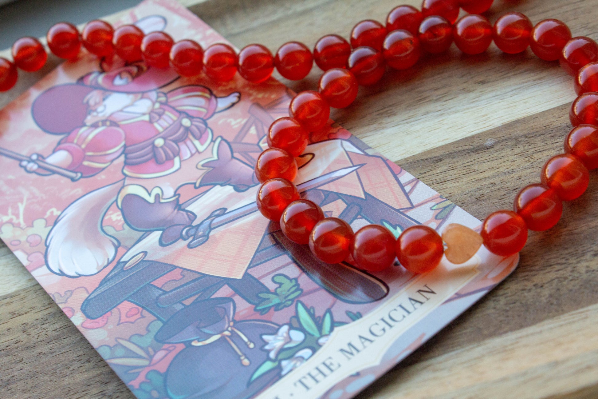 karneol ásványkarkötő, teremtő tűz energiával, spirituális ékszer, a háttérben mágus tarot kártyával