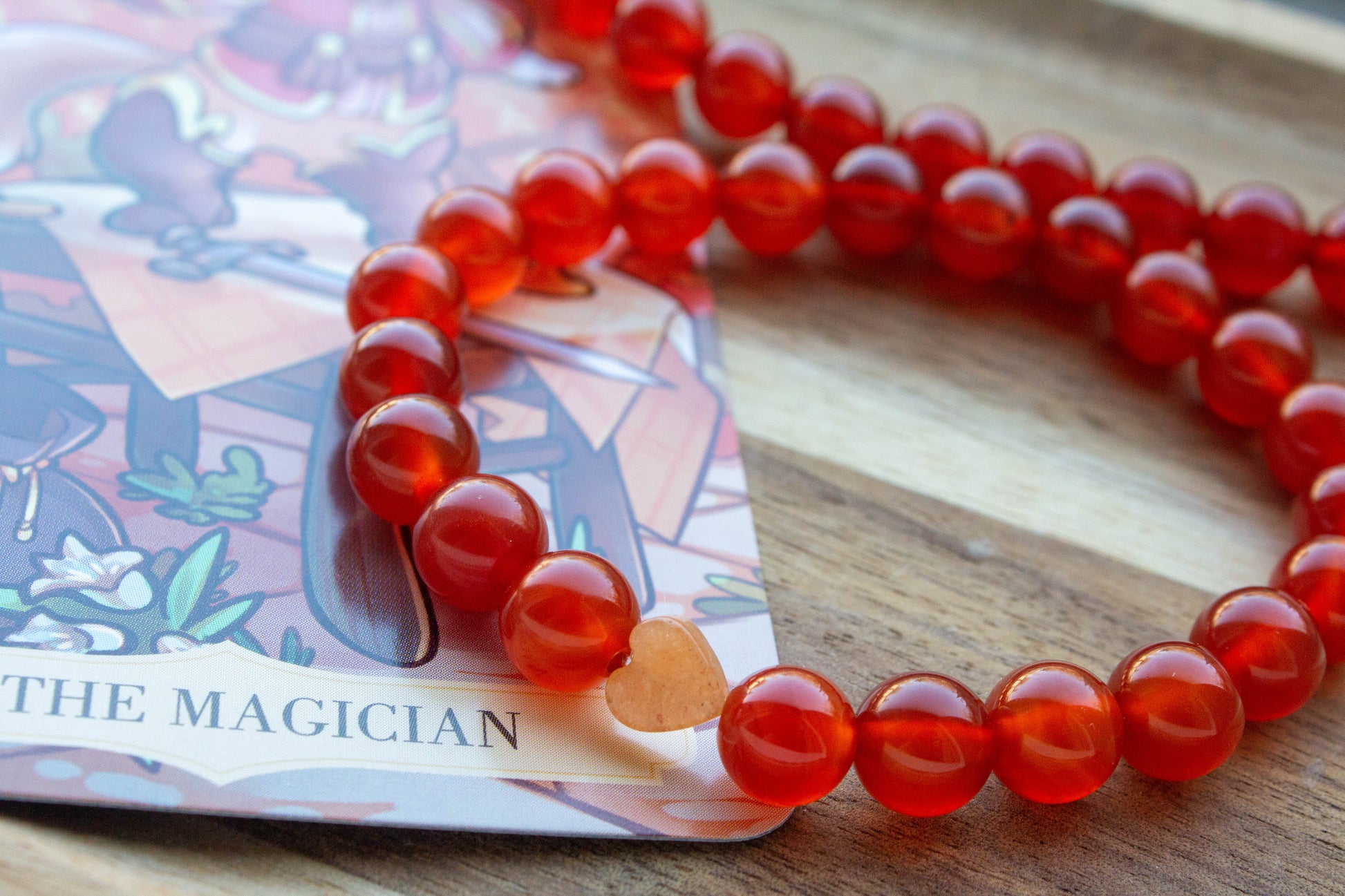 karneol ásványkarkötő, teremtő tűz energiával, spirituális ékszer, a háttérben mágus tarot kártyával