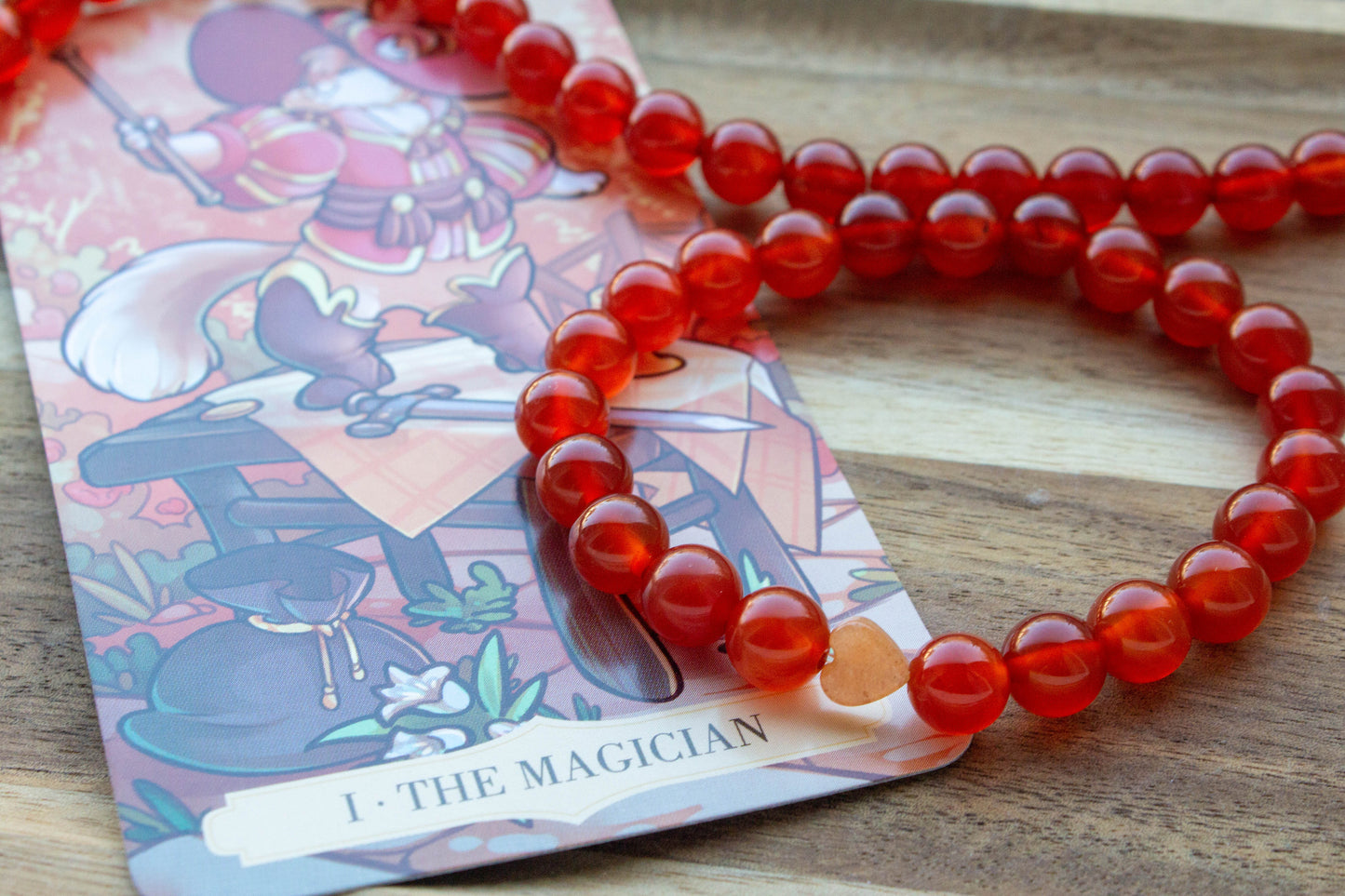 karneol ásványkarkötő, teremtő tűz energiával, spirituális ékszer, a háttérben mágus tarot kártyával