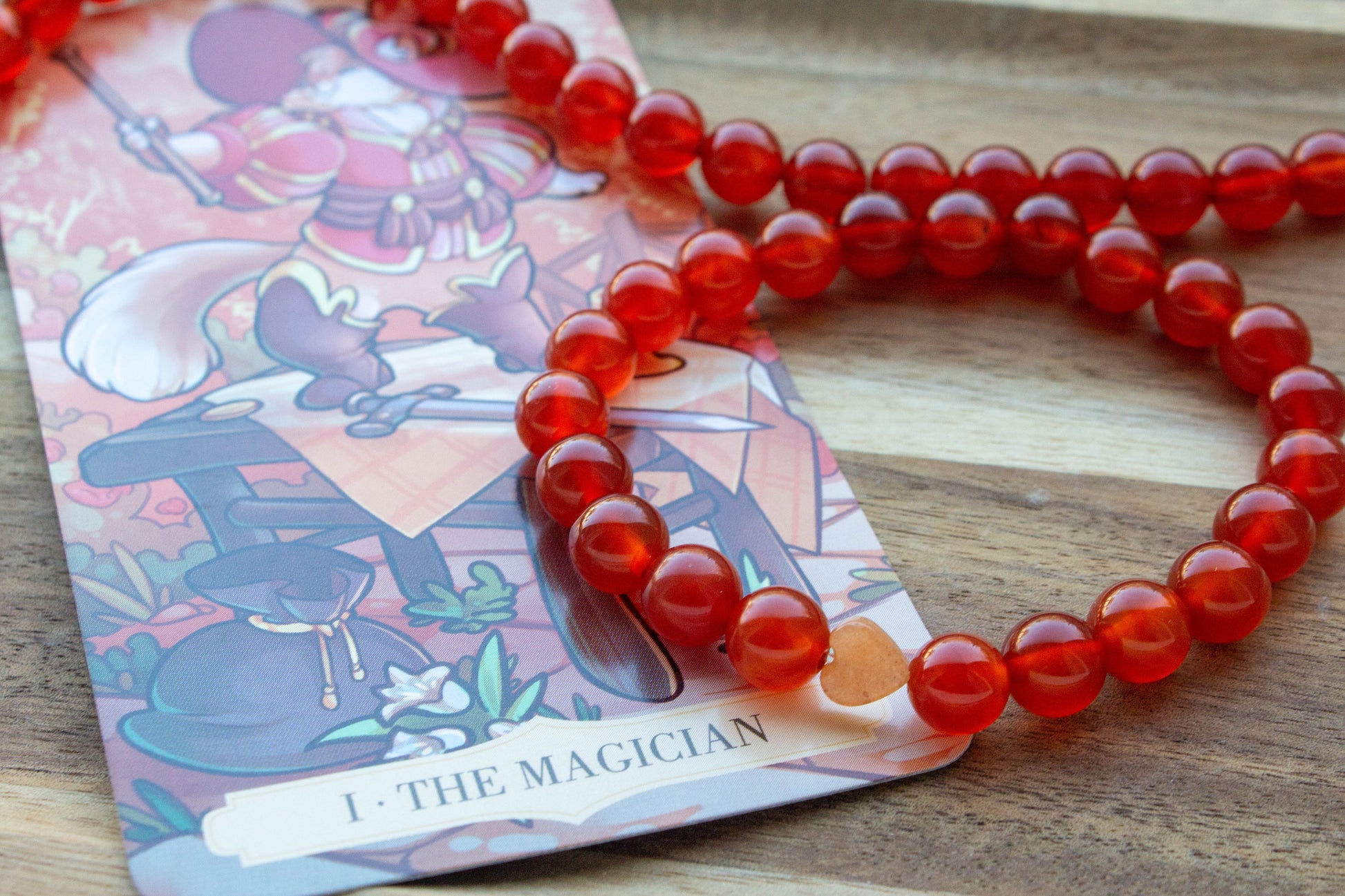 karneol ásványkarkötő, teremtő tűz energiával, spirituális ékszer, a háttérben mágus tarot kártyával